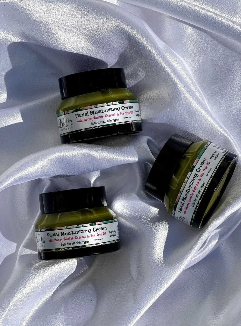 Two jars of facial moisturizing cream on a white satin background