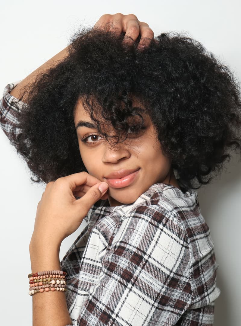 Person with curly hair wearing a plaid shirt against a plain background