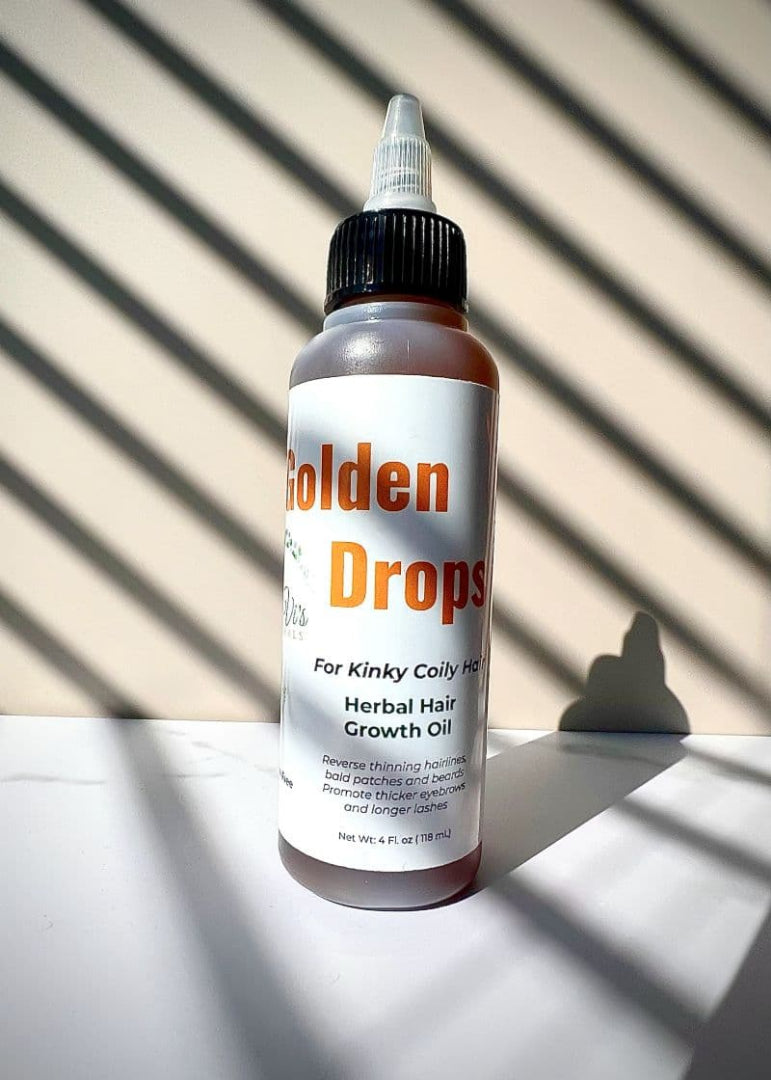 Bottle of Golden Drops herbal hair growth oil on a light background with shadows.