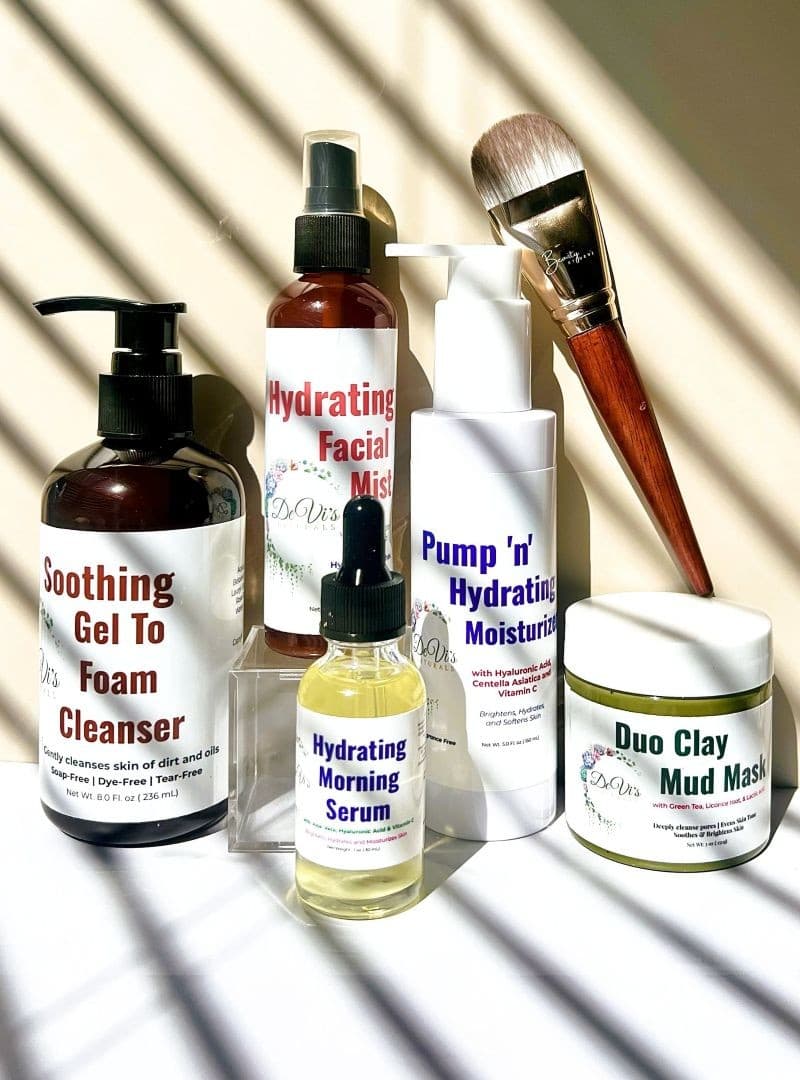 Collection of skincare products including bottles, jars, and a brush on a neutral background