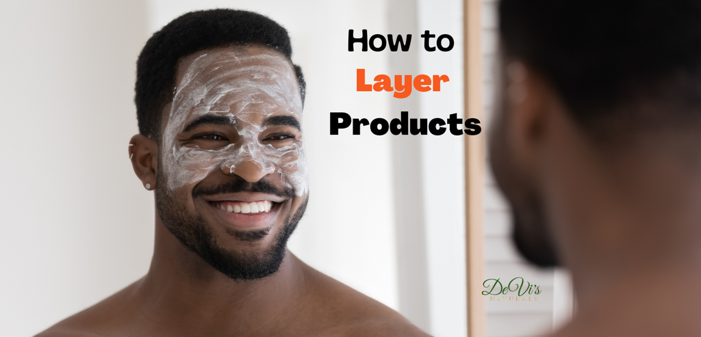Mirror reflection of african american man smiling with white facial mask on face. text saying how to layer products and DeVi's Naturals logo