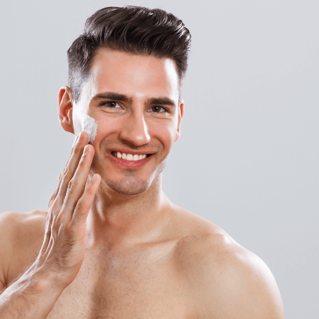 white man smiling applying moisturizer to right cheek 