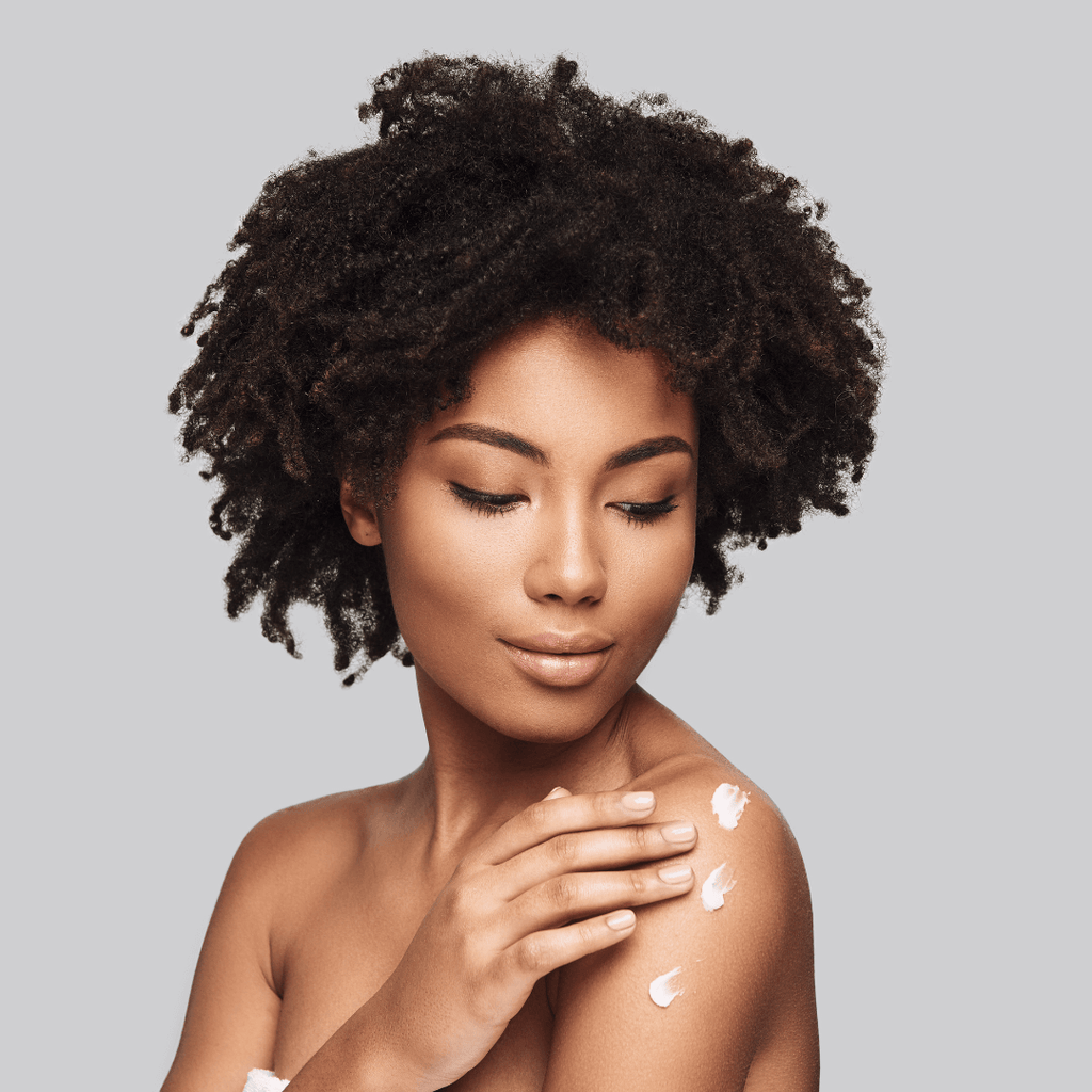portrait of beautiful black woman with moisturizer on shoulder 