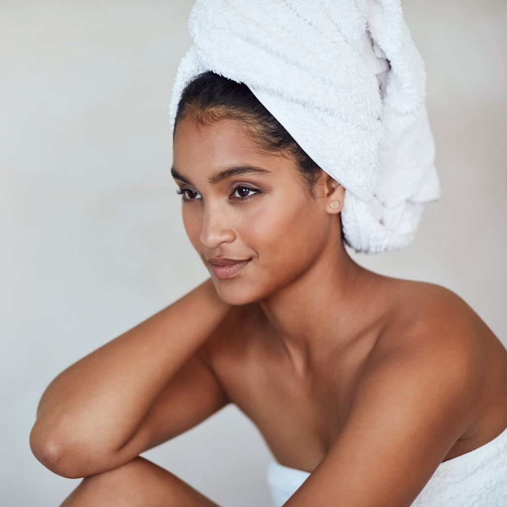 Gorgeous black woman wrapped in white towel sitting with white towel wrapped on head 