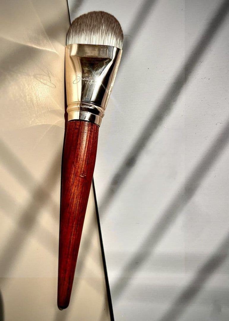 Makeup brush with wooden handle and metallic ferrule on a reflective surface