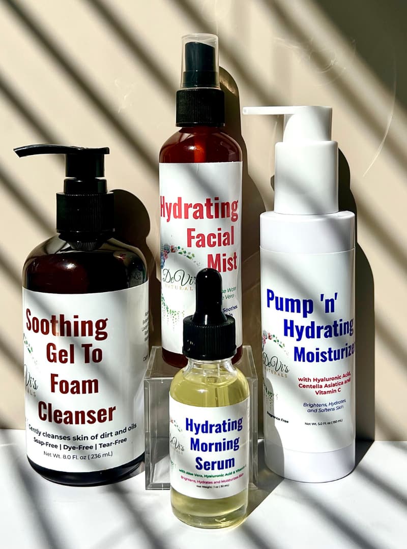 Set of skincare products including a gel to foam cleanser, facial mist, moisturizer, and serum on a neutral background.