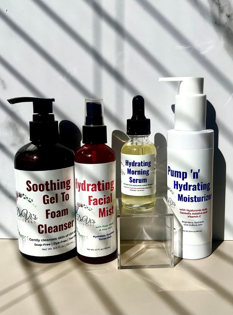 Set of skincare products including a cleanser, mist, serum, and moisturizer on a neutral background.