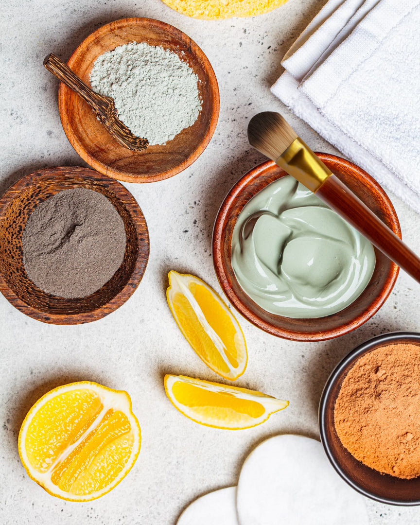 Facial treatment ingredients including a bowl of yellow cream, turmeric powder, honey, and lemons on a light surface.